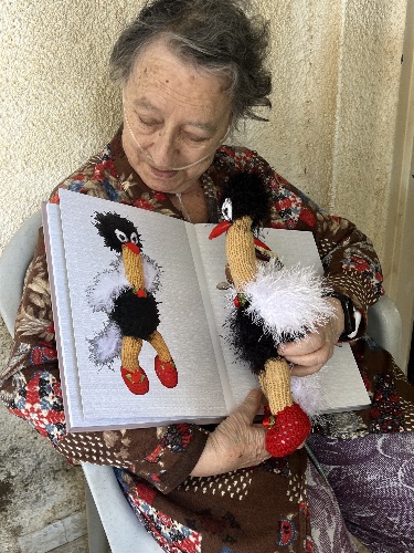 סבטלנה גנקין עם אחת מבובותיה הסרוגות, מגלה אותה מחדש בין דפי האלבום